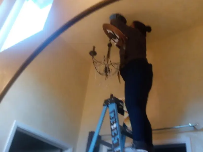 Electrician installing a chandelier in a Shelby residence